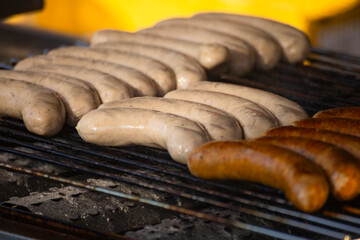 On the grill, sausages of various colors are neatly arranged