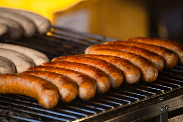 On the grill, sausages of various colors are neatly arranged