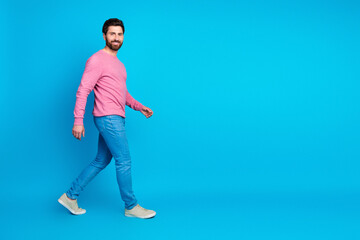 Confident man walking casually in stylish outfit against a vibrant blue background