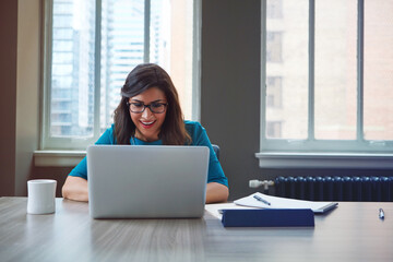 Business, female financial advisor and happy with laptop for clients savings plan review, reading profit data and revenue. Office, woman and smile at desk for wealth management or investment strategy