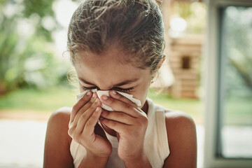 Face, child and girl crying in tissue at home with sad tears, spring allergy or flu virus in morning. Cold, sinus infection and sick young kid blowing nose with paper, health and wellness in house