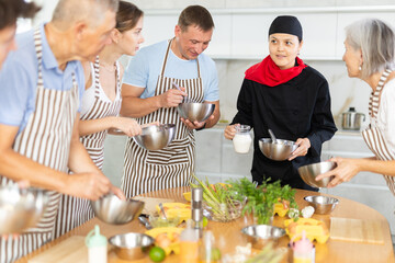 Young woman cook in uniform teaches group of different people how to cook dish
