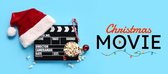 Clapperboard with Santa hat and popcorn on blue background. Christmas movie concept