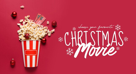 Bucket of popcorn with cinema tickets and Christmas tree balls on red background