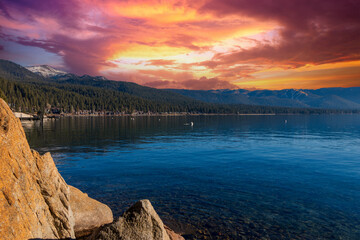 a gorgeous winter landscape at Lake Tahoe with blue lake water, lush green trees and plants and...