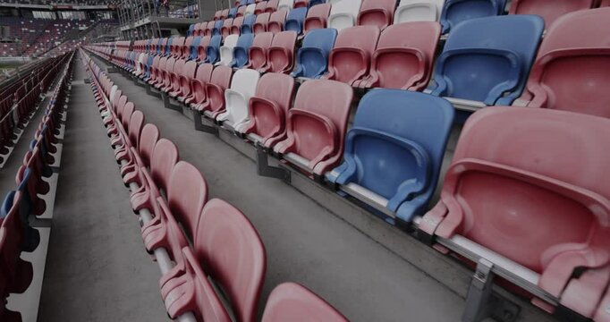 Empty stands in a modern football stadium with red, blue, and white seats in Silesia Poland, dynamic shot in 4K