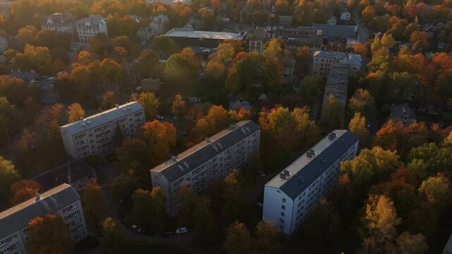 Aerial view of Soviet-era apartment blocks surrounded by autumn trees at sunrise