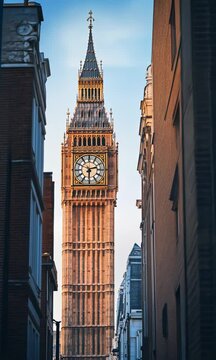 View of Big Ben from a narrow London street during sunset highlighting the iconic clock tower&rsquo;s stunning architecture