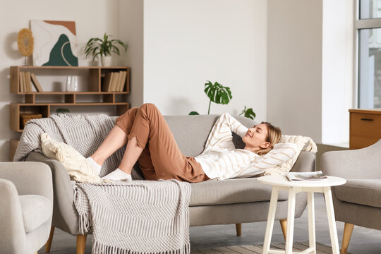 Young woman resting on grey sofa at home