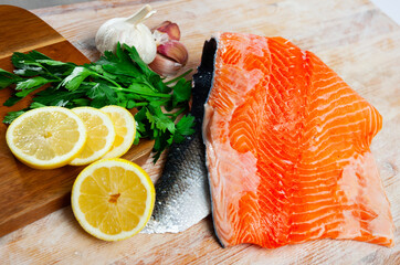 Raw salmon fillet lying on wooden table with condiments. Cooking ingredients