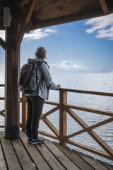 backpacking traveler viewing a snow-capped mountaintop from a pier. Traveler in Osorno Volcano