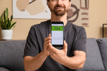 Diabetic man using mobile phone for measuring blood sugar level at home, closeup