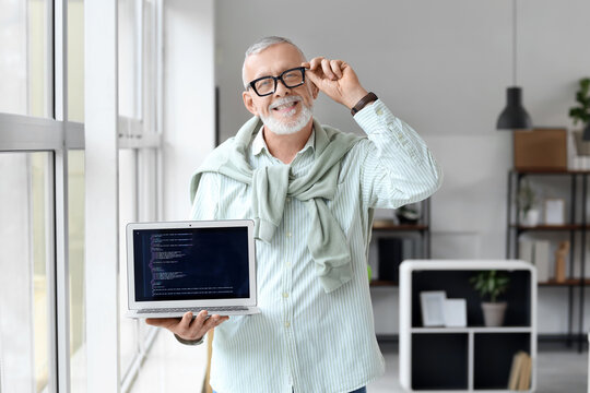 Mature programmer with laptop near window in office