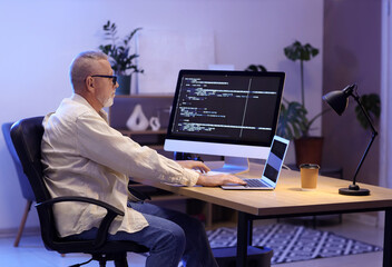 Mature programmer working in office at night