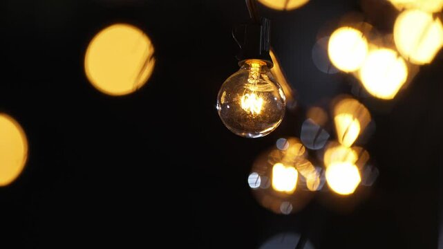 Sphere Light bulb, represent unity and harmony, on electricity wire, decorated by lovely family for holiday or anniversary celebration, illuminate in the outdoor dinner party at night. Divergence.