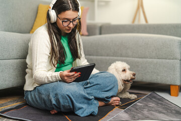 Young woman reading e-book and listening music with pet companion at home