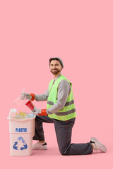 Male scavenger throwing plastic garbage into trash bin on pink background