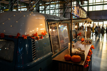 Festively decorated coffee shop in minibus with pumpkins and autumn leaves inside mall market. Cozy...