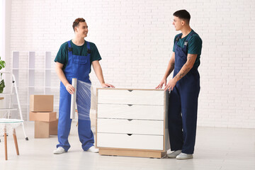 Male loaders wrapping commode with stretch film in room