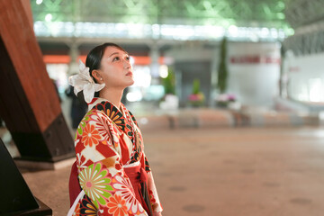 A Japanese woman in her 20s sits at an illuminated train station in Kanazawa, Ishikawa Prefecture, wearing a red kimono (hakama), a staple for Japanese university graduates.