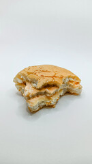 A close-up of a partially eaten burger featuring a sesame seed bun, creamy sauce, and a plain white backdrop.