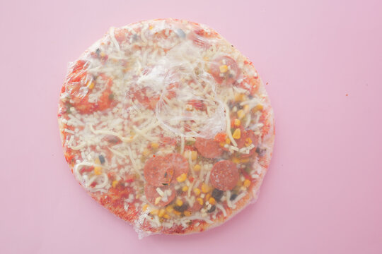 Delicious Frozen Pizza Featuring Cheese and Various Toppings, All Wrapped Securely in Plastic