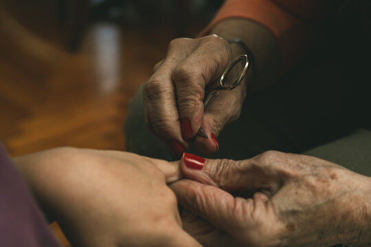 A granddaughter and her grandmother cutting her fingernails - Powered by Adobe
