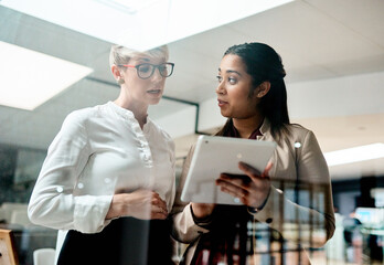 Obraz premium Window, meeting and business women on tablet in office for discussion, talking and planning. Professional, corporate and workers on digital tech for research project, online website and teamwork