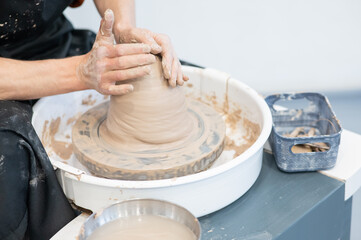 Close-up of a potter's hands working on a pottery wheel. 