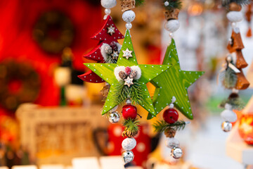 Colorful wooden star ornaments in green and red, adorned with pinecones, small bells and festive...