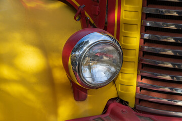 Headlight on an old yellow and red car