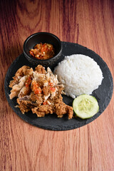 Ayam Geprek is an Indonesian dish of crispy fried chicken smashed with spicy sambal, often served with rice. It's a mix of crunchy, savory, and fiery flavors.