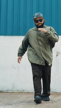 Skilled hipster doing cart wheel while multicultural friends encourage him. Hip-hop dancer moving foot step to music surrounded by group of hipster at wall near street. Outdoor sport 2024. hiphop.
