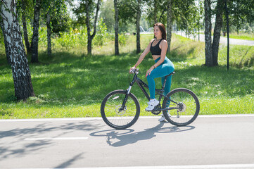 Naklejka premium Caucasian woman riding a bike in a park. 