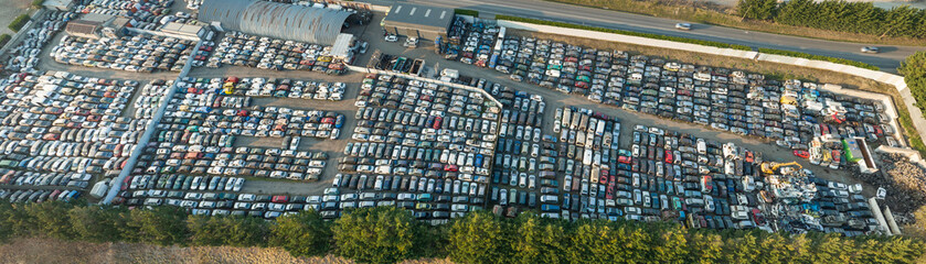 Aerial view of big parking lot of junkyard with rows of discarded broken cars. Recycling of old vehicles