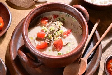 Soto Betawi is a creamy, coconut milk-based soup from Jakarta Indonesia, featuring beef or offal, potatoes, and spices, served with rice, lime, and sambal - selective focus