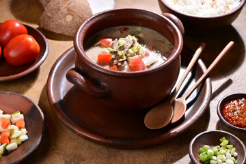 Soto Betawi is a creamy, coconut milk-based soup from Jakarta Indonesia, featuring beef or offal, potatoes, and spices, served with rice, lime, and sambal - selective focus