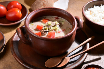 Soto Betawi is a creamy, coconut milk-based soup from Jakarta Indonesia, featuring beef or offal, potatoes, and spices, served with rice, lime, and sambal - selective focus