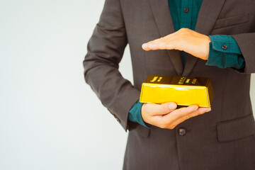 Close-up of a businessman holding shiny gold bars, symbolizing wealth and investment, isolated on a...