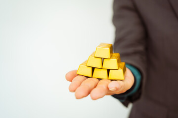 Close-up of a businessman holding shiny gold bars, symbolizing wealth and investment, isolated on a...