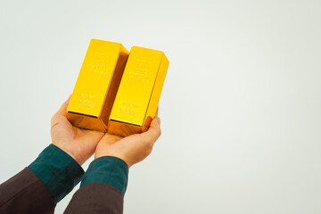 Close-up of a businessman holding shiny gold bars, symbolizing wealth and investment, isolated on a...