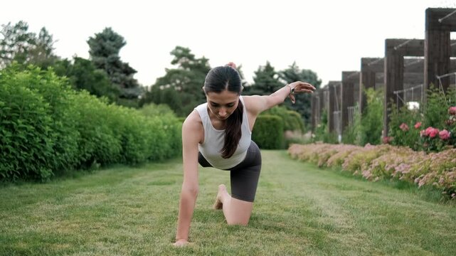 Young woman practicing yoga in a serene garden, displaying an elegant pose surrounded by vibrant greenery and colorful blossoms