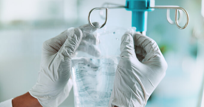 Healthcare, hands and doctor in hospital with IV drip, cancer treatment and medicine in bag. Person, specialist and liquid medication in clinic for infusion therapy, healing and gloves for protection