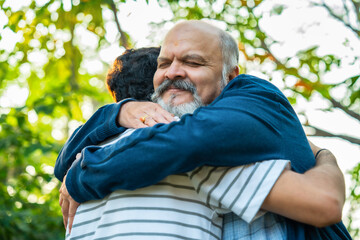 Indian Asian Happy Old Aged Father and Young Handsome Son Walking Closer to Embrace Each Other in Joyful Hug outdoors in the garden, Depicting Emotional Father-Son Bonding Outdoors