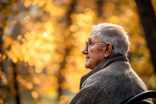 Reflective moment: elderly man in autumn park for world Parkinson's day awareness. Old person symbolizing brain dysfunction. Degenerative disorder. World Alzheimer's Day. Horizontal banner. Copy space - Powered by Adobe