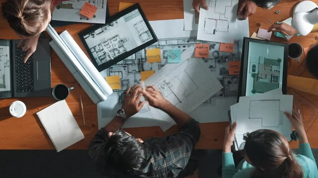 Top down view of manager writing project plan and sitting at meeting. Aerial view of business people planning and sharing idea about house construction at table with laptop and equipments. Symposium.