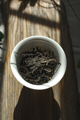 Dried Tea Leaves Beautifully Arranged in a White Bowl Placed on a Rustic Wooden Table