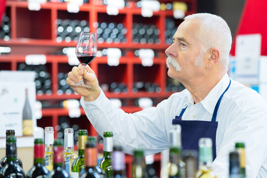 senior man worker tasting red wine