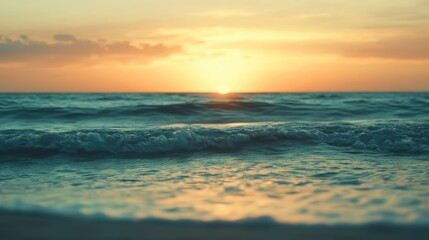 Obraz premium Serene tropical sunset over ocean waves with a soft blur effect creating a tranquil atmosphere in horizontal orientation