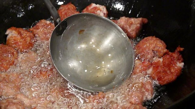 뜨거운 기름에 국자로 고기완자를 튀기는 장면